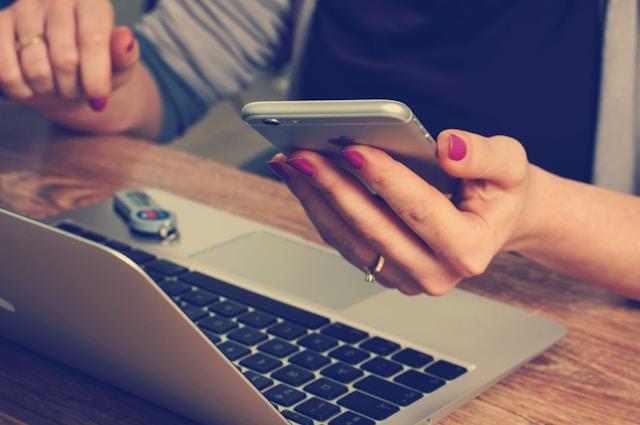Raising a job on a phone beside a laptop